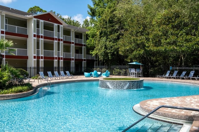 Building pool lounge chairs and blue chairs exterior at Lux 13 in Gainesville Student Accommodation