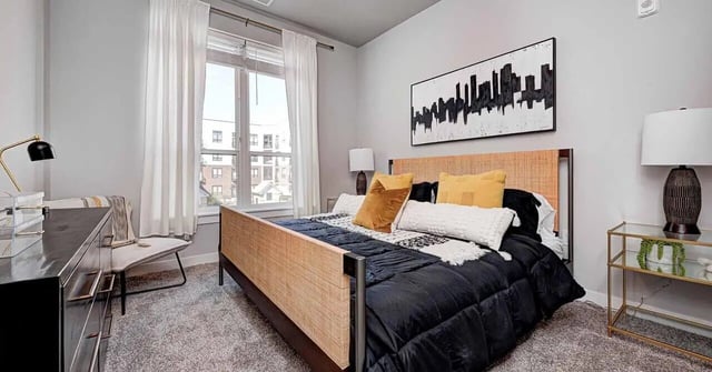 Bed with black bedding yellow pillows and artwork bedroom at Continuum Apartments in Gainesville Student Accommodation