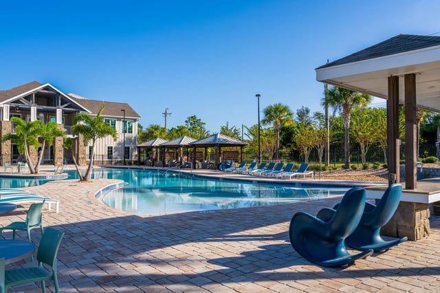 Blue chairs poolside with loungers and cabanas pool at The Retreat at Tampa in Tampa Student Accommodation