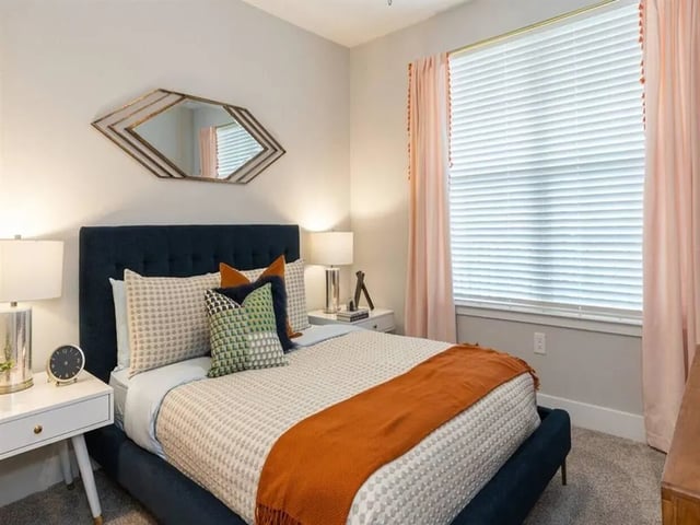 Dark blue bed with patterned bedding and orange throw bedroom at Alvista West Vue in Orlando Student Accommodation