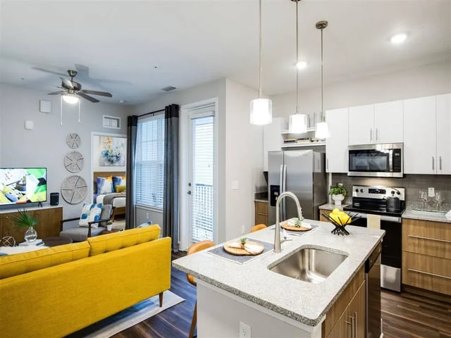 Yellow couch stainless steel appliances kitchen living room at Alvista West Vue in Orlando Student Accommodation