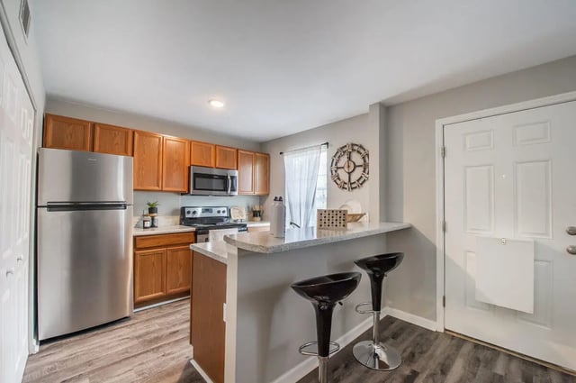 Stainless steel refrigerator wood cabinets counter with bar stools kitchen at Elevate on Cascade in Tallahassee Student Accommodation
