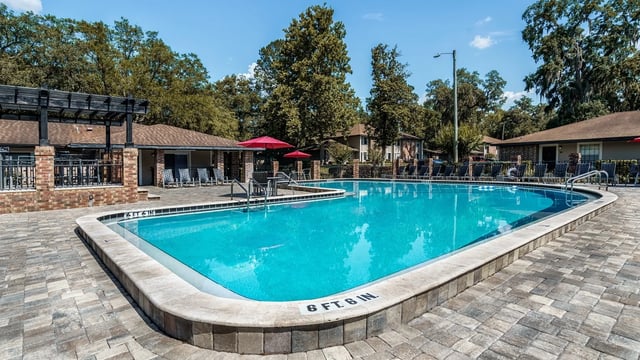 Pool lounge chairs red umbrellas poolside seating pool exterior at Oxford Manor in Gainesville Student Accommodation
