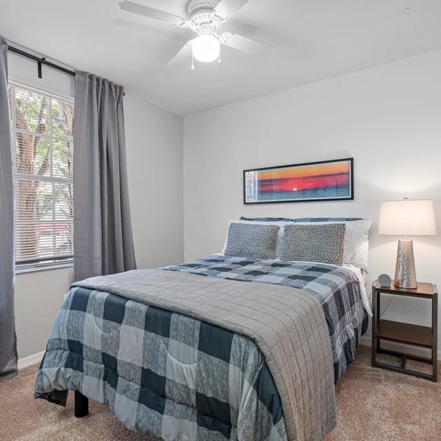 Bed with plaid bedding nightstand and artwork bedroom at VUE Tampa in Tampa Student Accommodation