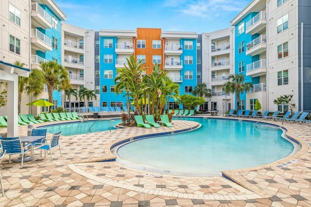 Colorful apartment buildings with pool and lounge chairs exterior at IQ Apartments in Tampa Student Accommodation