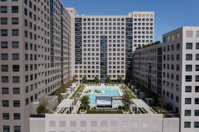 Modern buildings surround a pool and lounge area exterior at The One at University City in Miami Student Accommodation