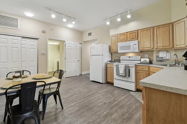 Table chairs refrigerator stove microwave kitchen at Malibu Apartments in Tampa Student Accommodation