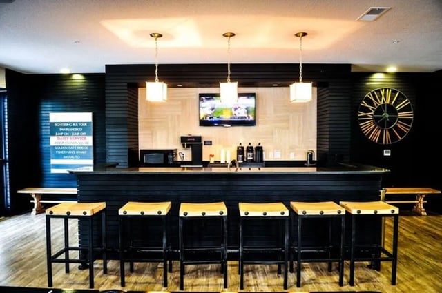 Bar with stools coffee maker TV and clock common area at The Flats at 4200 in Tampa Student Accommodation