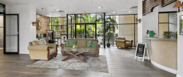 Sofa armchairs coffee table welcome sign reception area. at Malibu Apartments in Tampa Student Accommodation