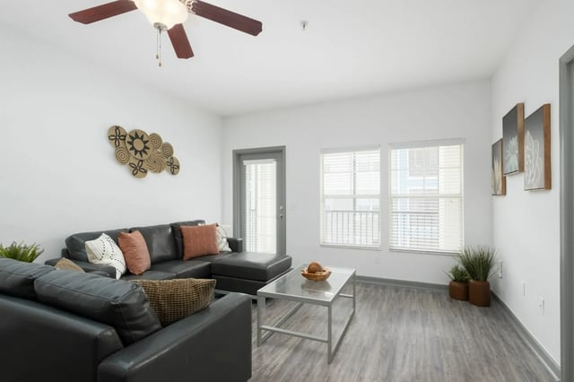 Gray sectional sofa with pillows glass coffee table living room at The Enclave in Gainesville Student Accommodation
