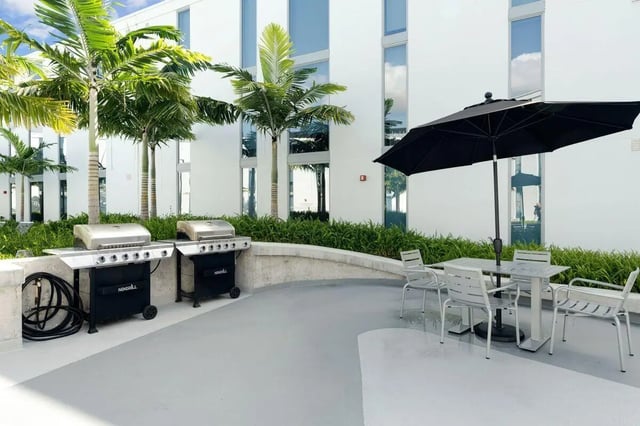 Grills table chairs umbrella and palm trees exterior at VOX Miami in Miami Student Accommodation