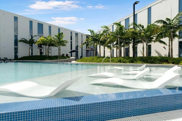 Modern building with pool and white lounge chairs exterior at VOX Miami in Miami Student Accommodation