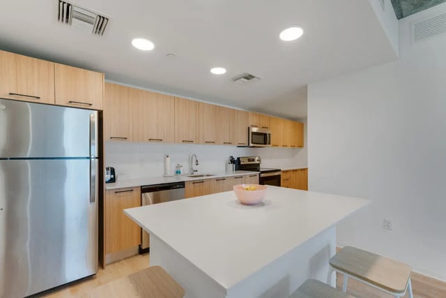 Stainless steel refrigerator modern cabinetry white island kitchen at VOX Miami in Miami Student Accommodation