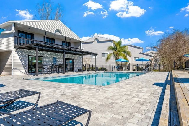 Pool lounge chairs umbrellas and building exterior exterior at Greenwich Green Aspen Ridge in Gainesville Student Accommodation