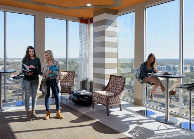 Students studying by large windows lounge area at The Standard at Gainesville in Gainesville Student Accommodation