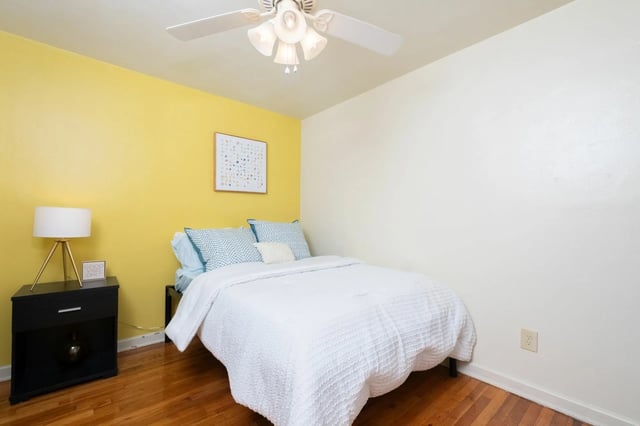 Bed with white comforter nightstand lamp bedroom at College Manor in Gainesville Student Accommodation