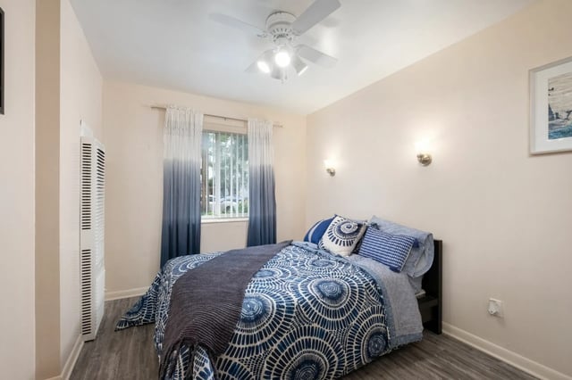 Bed with blue patterned bedding ceiling fan window bedroom at College Manor in Gainesville Student Accommodation