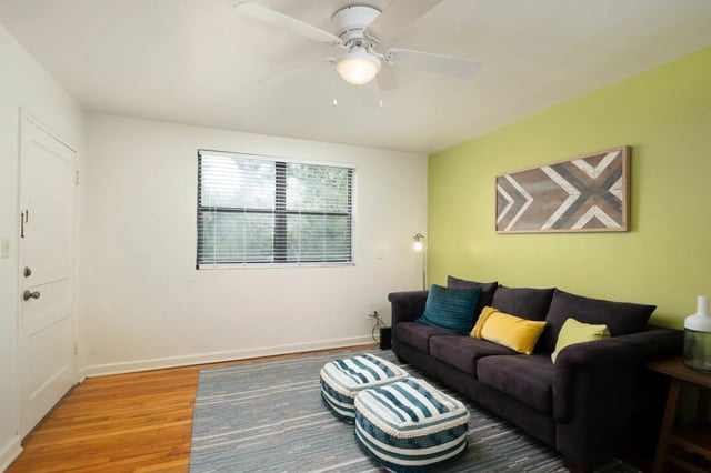 Dark sofa striped ottomans patterned wall living room at College Manor in Gainesville Student Accommodation