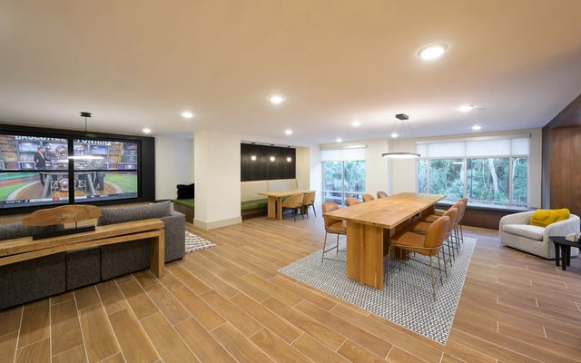 Large screen TV dining tables sofa living room at The Metropolitan Gainesville in Gainesville Student Accommodation