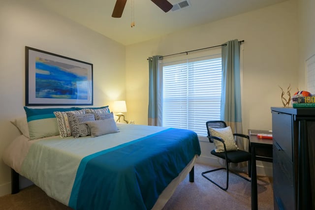 Bed desk chair and artwork bedroom at The Retreat at Gainesville in Gainesville Student Accommodation