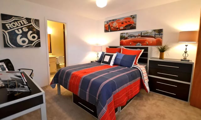 Bed with red and blue linens and car art bedroom at Spyglass Apartments in Gainesville Student Accommodation