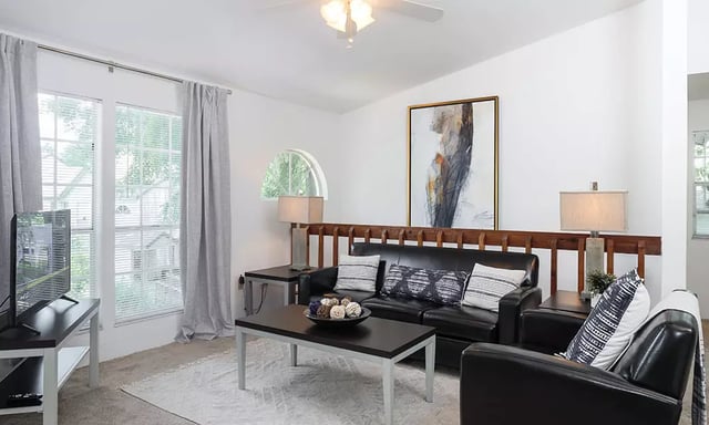 Black sofas coffee table artwork windows living room at Spyglass Apartments in Gainesville Student Accommodation