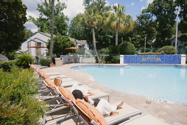 Lounge chairs by pool with palm trees exterior at Spyglass Apartments in Gainesville Student Accommodation