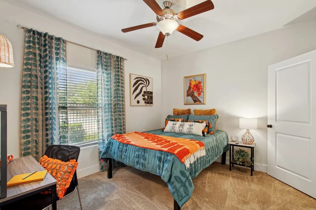 Bed with orange throw desk chair art bedroom at The Station Alafaya in Orlando Student Accommodation