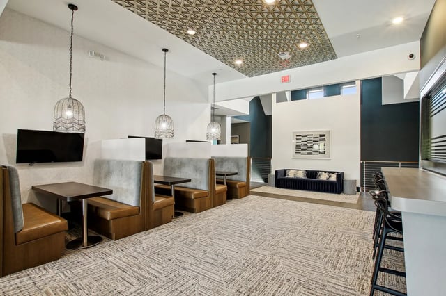 Booths televisions couch and bar stools common area at The Station Alafaya in Orlando Student Accommodation