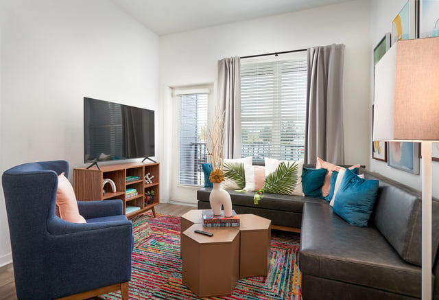 Sofa armchair TV bookshelf and rug living room at The Accolade Collegiate Village West in Orlando Student Accommodation