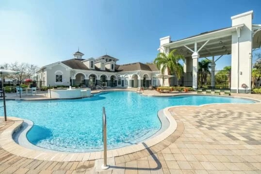 Large blue swimming pool with lounge chairs exterior at The Lofts Orlando in Orlando Student Accommodation