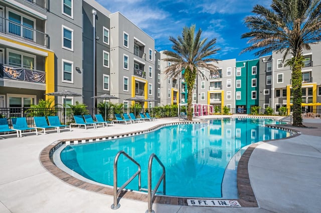 Pool with lounge chairs and palm trees exterior at The Aves @ Twelve 100 in Orlando Student Accommodation
