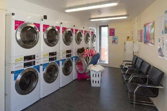 Washers and dryers with seating area laundry room at Denton Holme in Carlisle Student Accommodation
