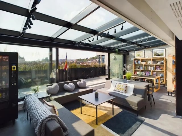 Modern lounge with sofas tables and bookshelf common area at Ravilious House in Brighton Student Accommodation