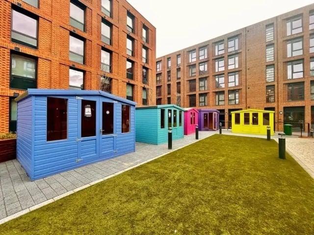 Colorful sheds on paved courtyard exterior at Guilden Village in Guildford Student Accommodation