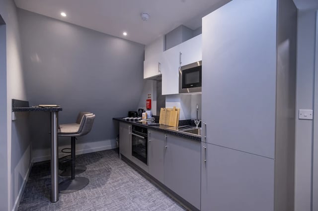 Modern kitchen with bar stool microwave and cabinets Kitchen at Ash Grove Court - Guildford in Guildford Student Accommodation