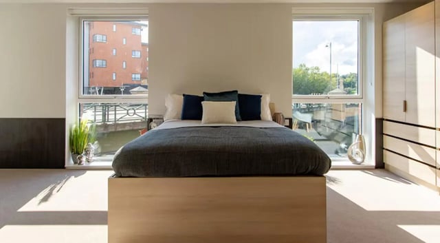 Bed with pillows wardrobe and large windows bedroom at Hythe Mills in Colchester Student Accommodation