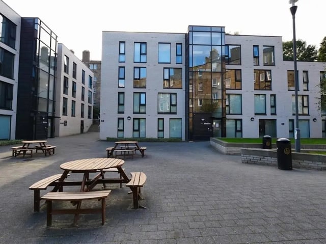 Wooden picnic tables in paved courtyard exterior at Gateway Apartments in Edinburgh Student Accommodation