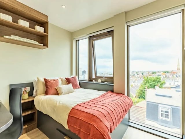 Bed desk chair shelves overlooking cityscape bedroom at Crown House Brighton in Brighton Student Accommodation