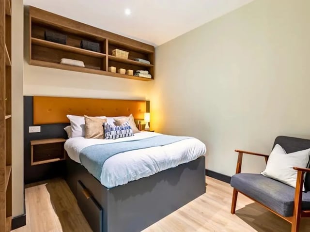 Bed bedside table shelves and chair bedroom at Crown House Brighton in Brighton Student Accommodation