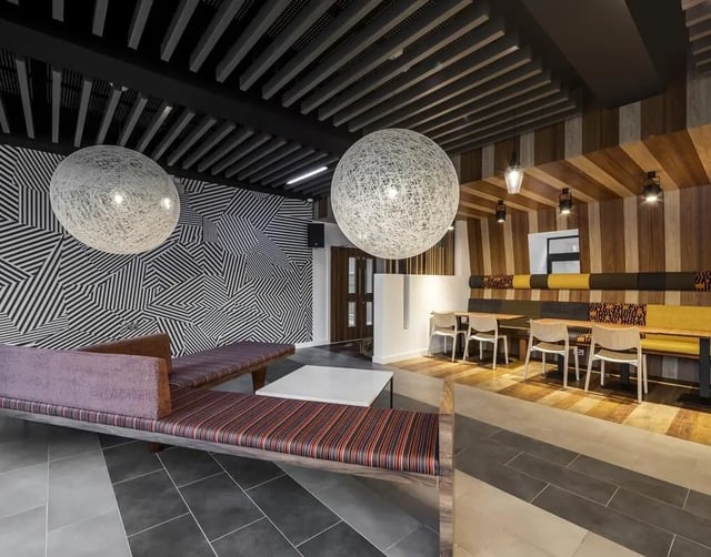 Modern lounge area with striped seating and tables lounge area at Collegiate Plummer House in Newcastle Upon Tyne Student Accommodation