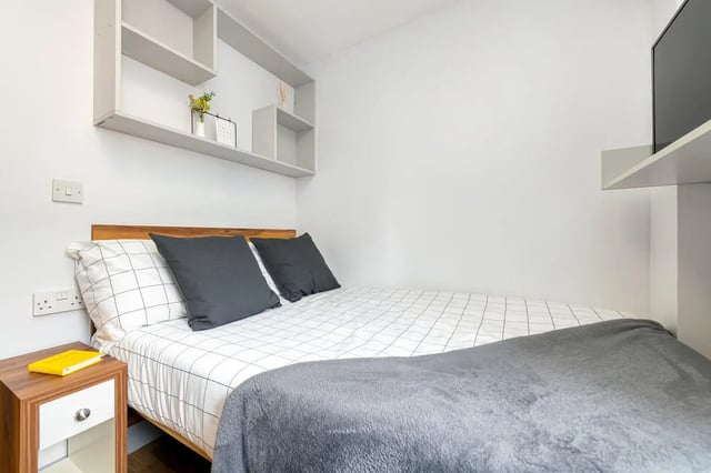 Bed with grey pillows and shelves bedroom at Collegiate St James Street in Portsmouth Student Accommodation