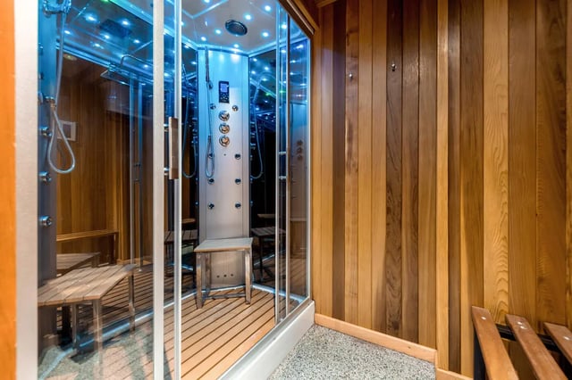 Glass steam shower with wooden benches and benches steam room at Collegiate Castle Street in Cambridge Student Accommodation