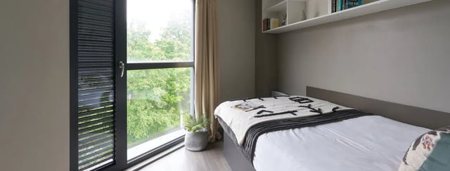 Bed with blanket window plant shelf books bedroom at Gosford Gate in Coventry Student Accommodation