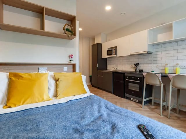 Bed with yellow pillows and kitchen studio living room at Yugo St. Crispin's House in Norwich Student Accommodation