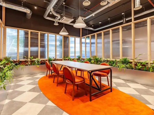 Table with orange chairs plants and checkered floor common area at Yugo St. Crispin's House in Norwich Student Accommodation