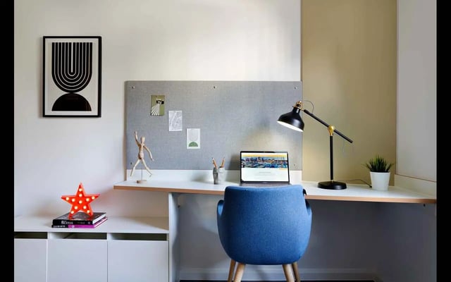 Desk with laptop, blue chair, artwork, study area at Hampton Square in Southampton Student Accommodation