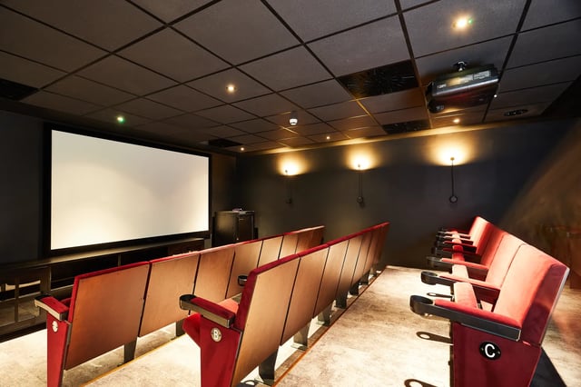 Red theater seats facing blank screen projector Cinema room at Vita Student Pebble Mill in Birmingham Student Accommodation
