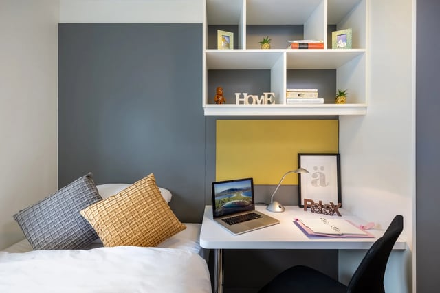Bed with pillows laptop and desk study area at Cuirt na Coiribe in Galway Student Accommodation