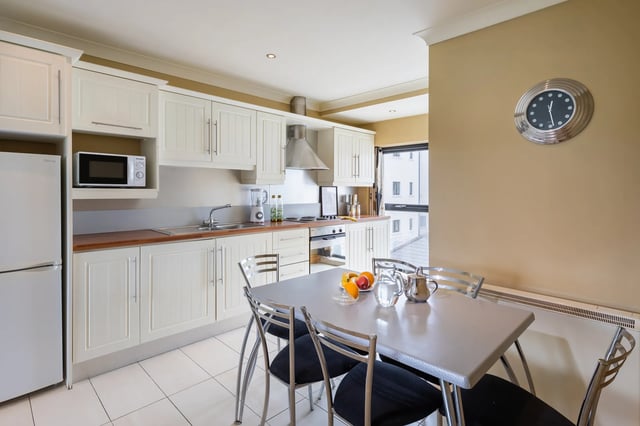 White cabinets fridge microwave table chairs fruit kitchen at Cuirt na Coiribe in Galway Student Accommodation
